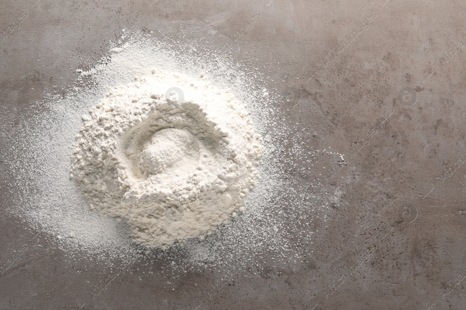 Photo of Pile of flour on grey textured table, top view. Space for text