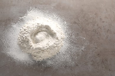 Pile of flour on grey textured table, top view. Space for text