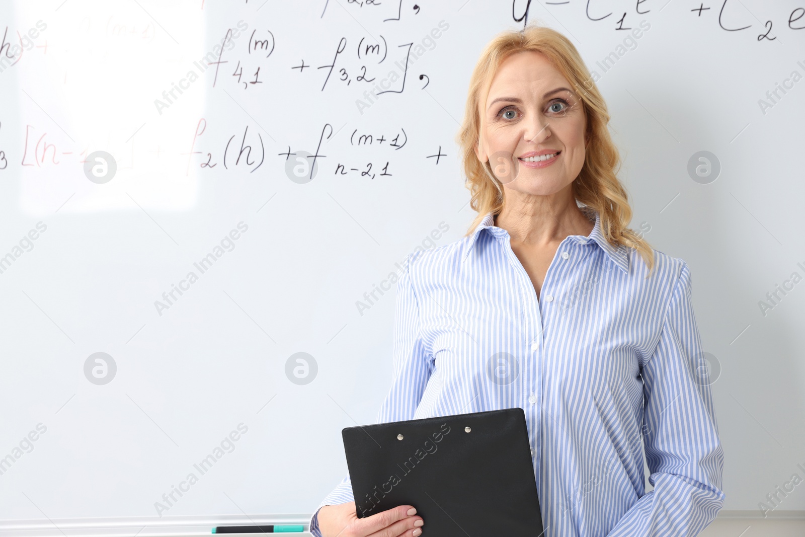 Photo of Happy mature professor with clipboard near whiteboard