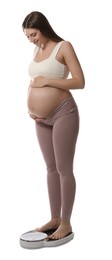 Pregnant woman standing on scales against white background