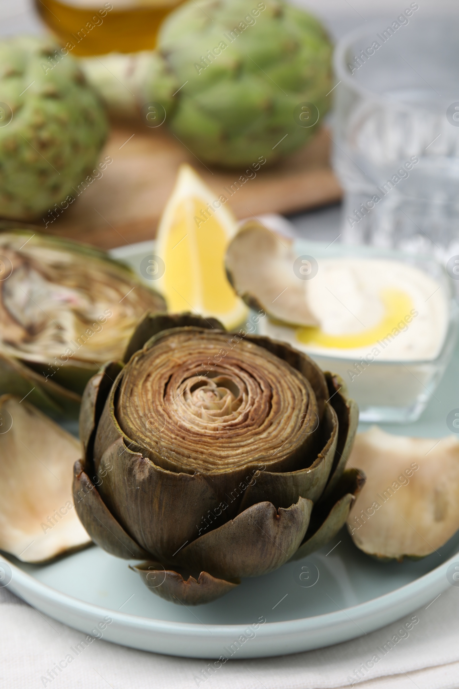 Photo of Delicious cooked artichoke with tasty sauce on table, closeup