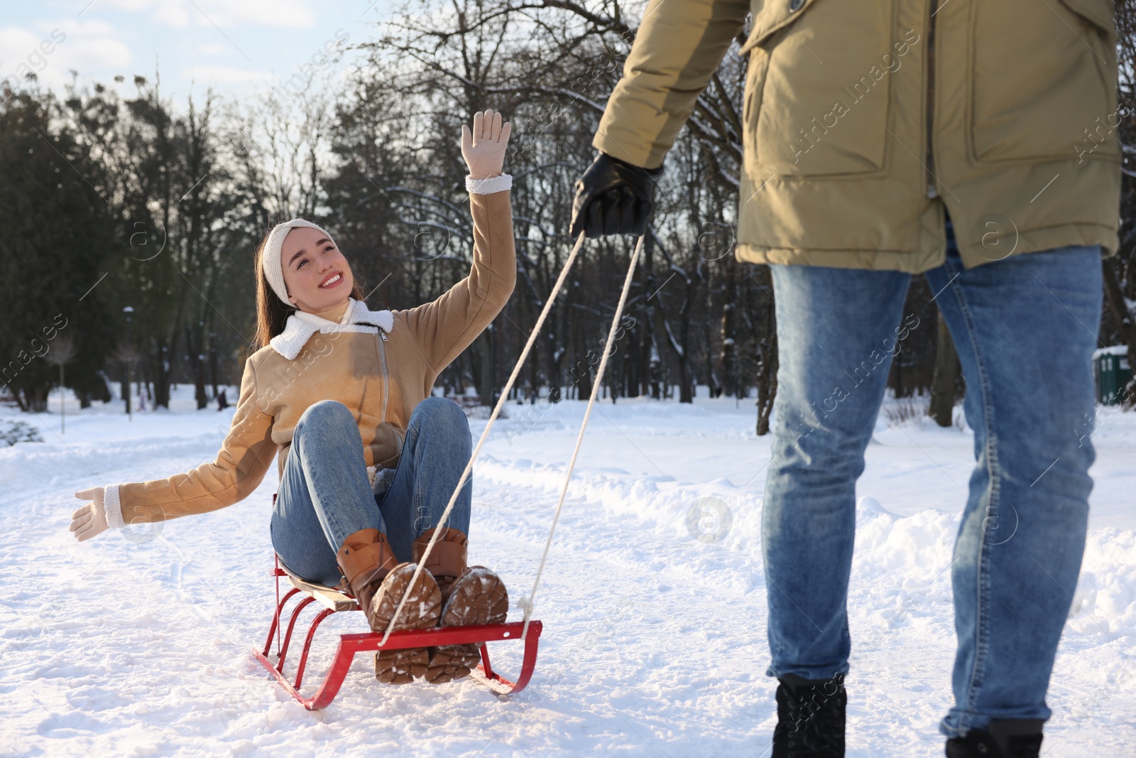 Photo of Man pulling his girlfriend in sleigh outdoors on winter day