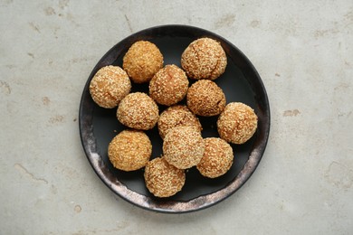 Delicious sesame balls on light grey textured table, top view