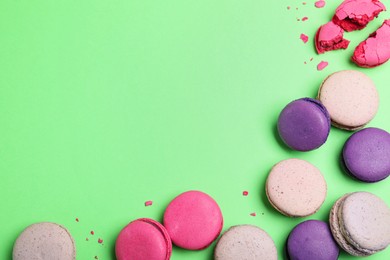 Delicious colorful macarons on green background, flat lay. Space for text