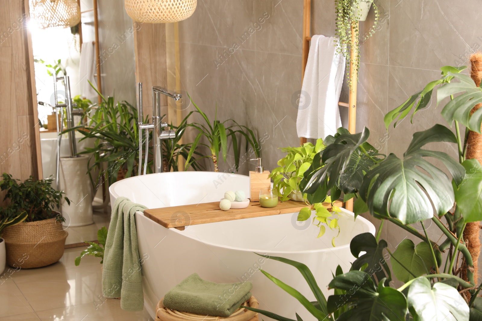 Photo of Modern white tub and beautiful green houseplants in bathroom. Interior design