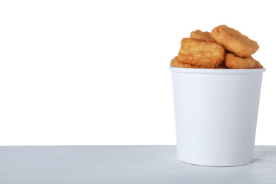 Bucket with tasty chicken nuggets on wooden table against white background. Space for text