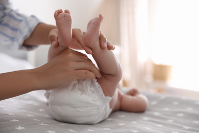 Photo of Mother changing her baby's diaper on bed