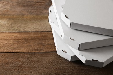 Photo of Stack of empty pizza boxes on wooden table, closeup. Space for text