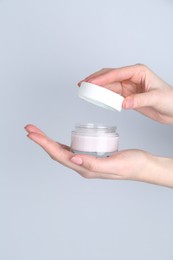 Woman with jar of cream on grey background, closeup