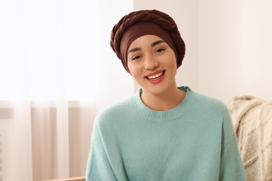 Photo of Cancer patient. Young woman with headscarf near window indoors, space for text