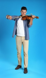 Photo of Happy man playing violin on light blue background