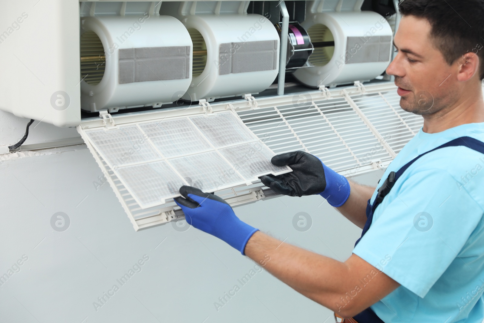 Photo of Male technician cleaning air conditioner indoors