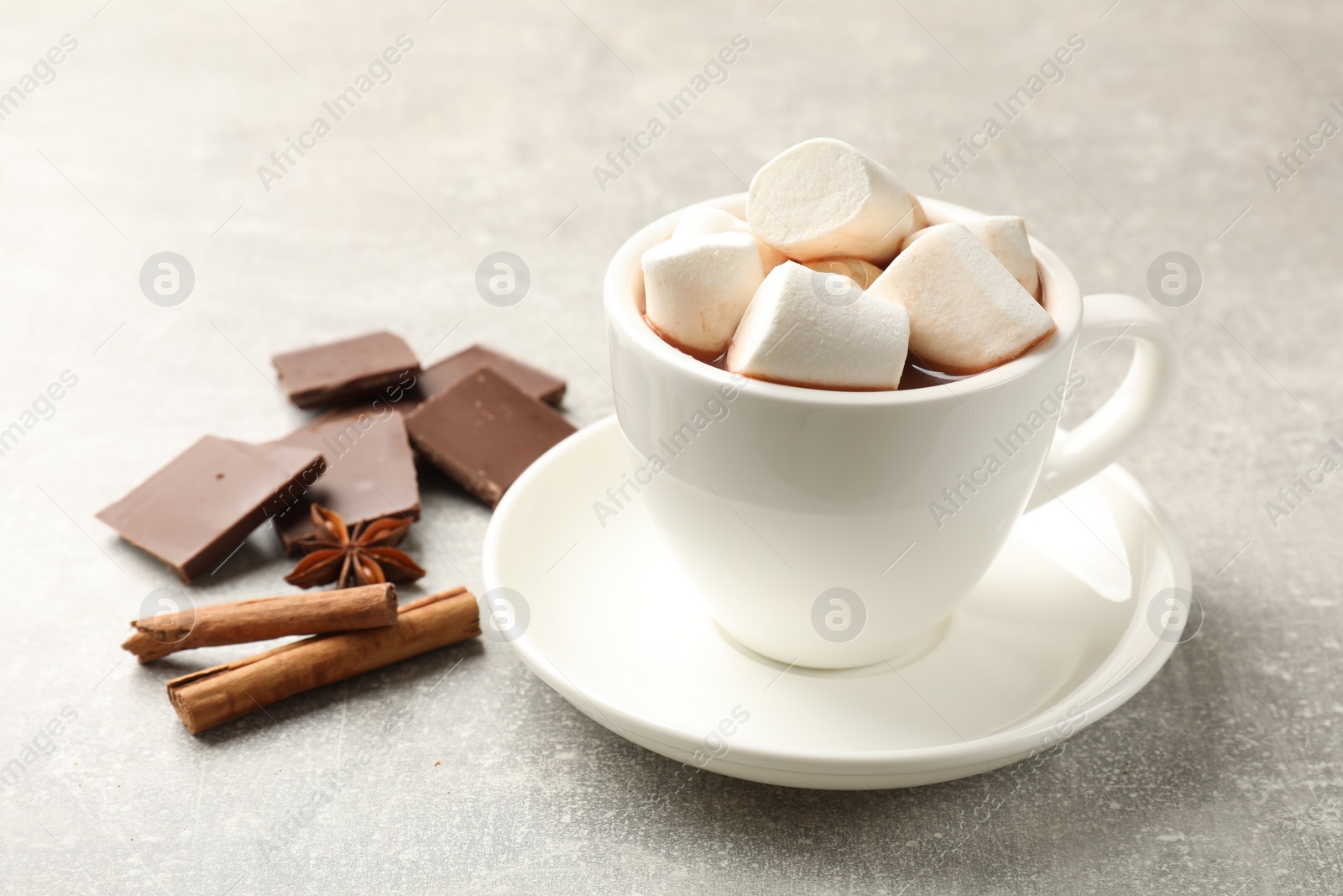 Photo of Tasty hot chocolate with marshmallows and ingredients on light grey table, closeup