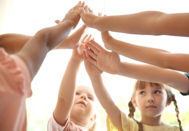 Photo of Little children putting their hands together on light background. Unity concept