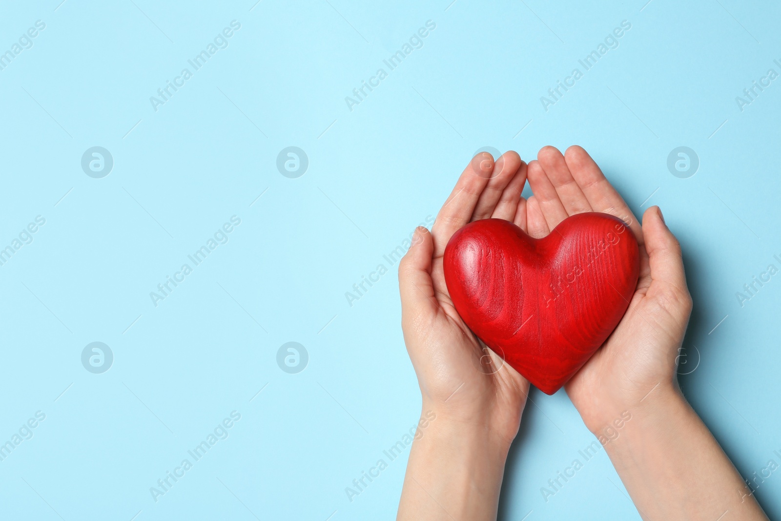 Photo of Woman holding heart on blue background, top view with space for text. Donation concept