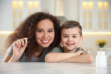 African-American woman and little boy with vitamin pill in kitchen