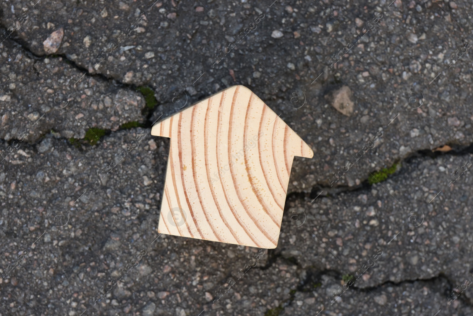 Photo of Wooden house model on cracked asphalt, top view. Earthquake disaster