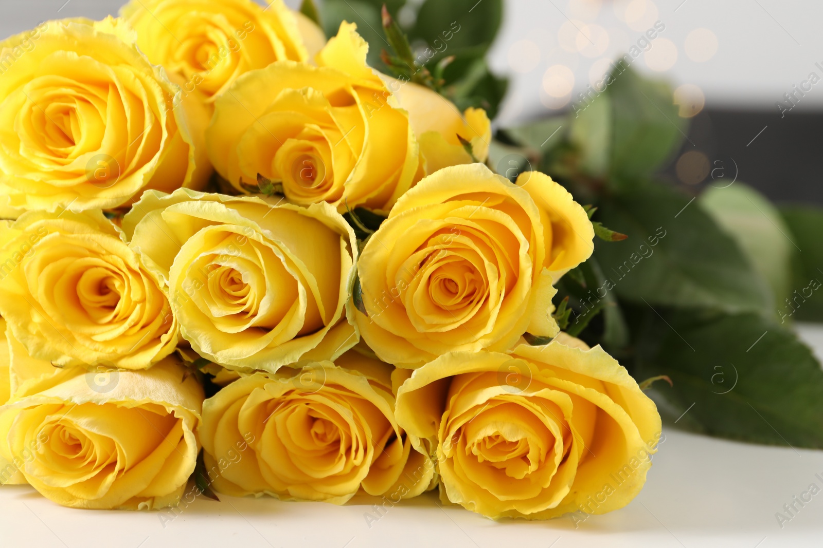 Photo of Beautiful bouquet of yellow roses on white table, closeup