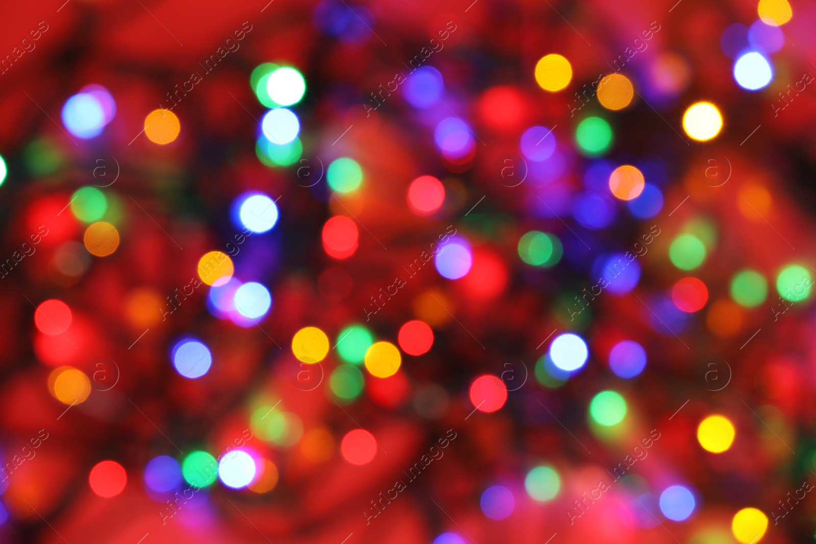 Photo of Blurred view of glowing Christmas lights on color background, top view