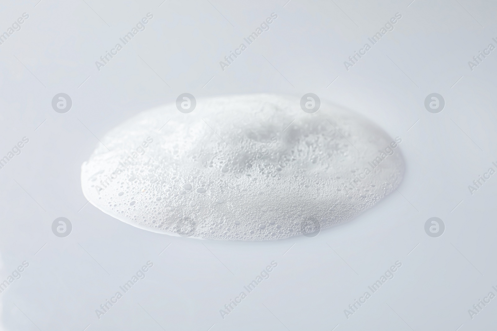 Photo of Drop of fluffy soap foam on white background