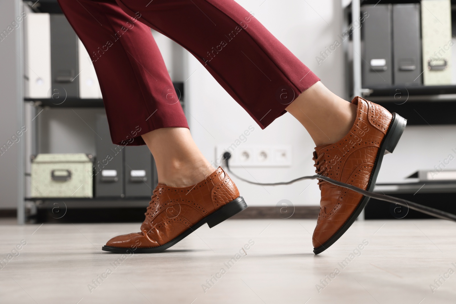 Photo of Woman tripping over cable in office, closeup