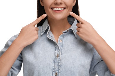Photo of Woman pointing at her clean teeth and smiling on white background, closeup