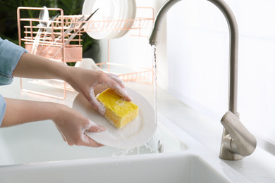 Photo of Woman washing plate in modern kitchen, closeup