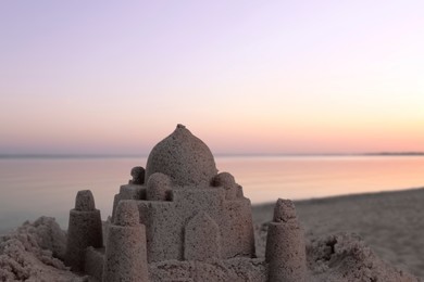 Image of Sand castle on ocean beach at sunset, space for text. Outdoor play