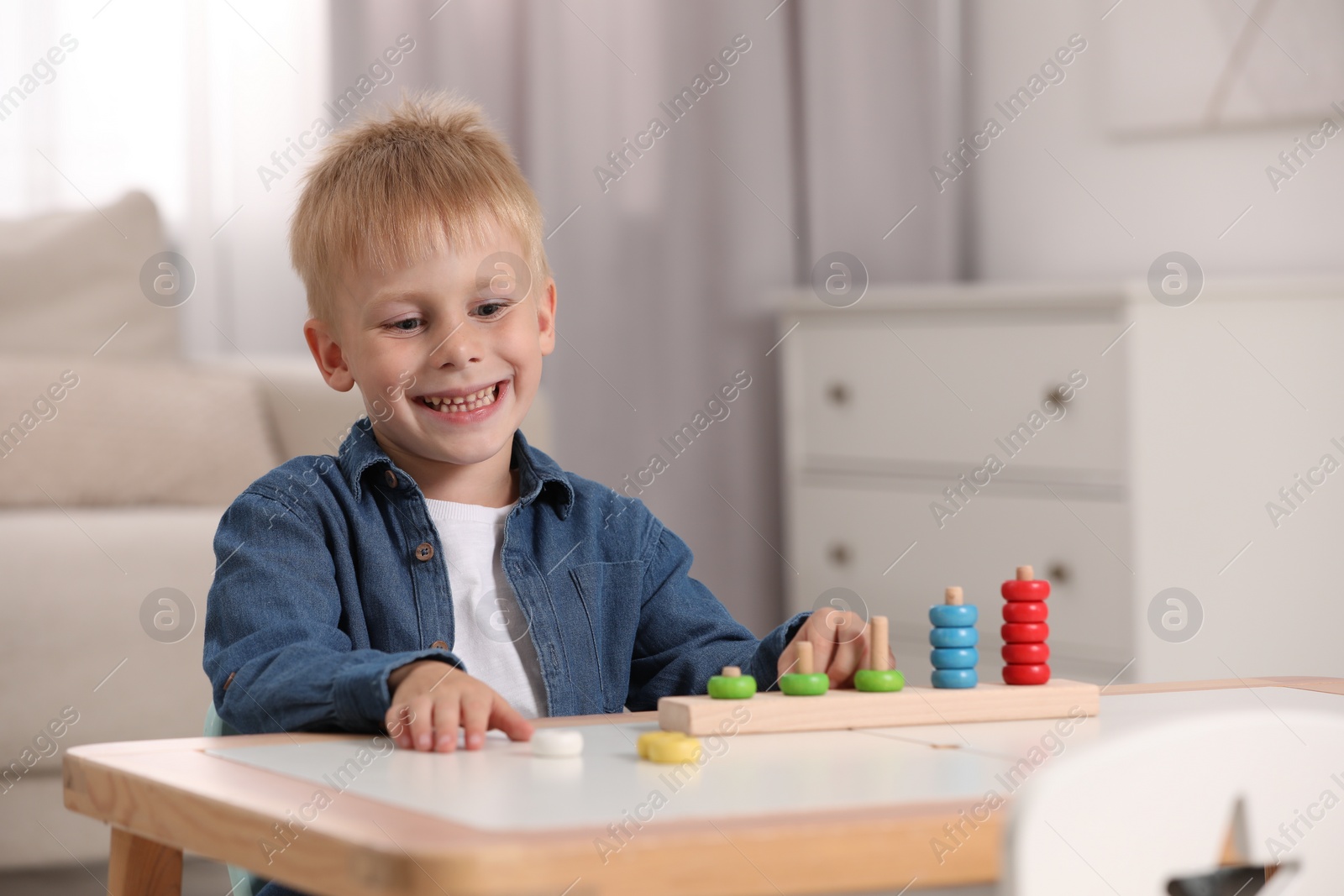 Photo of Cute little boy playing with stacking and counting game at table indoors, space for text. Child's toy