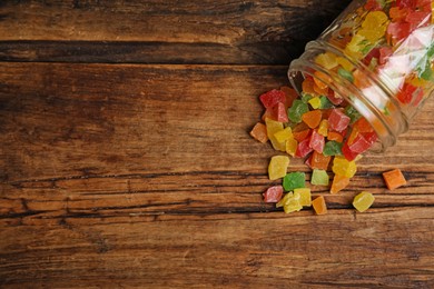 Overturned jar with mix of delicious candied fruits on wooden table, flat lay. Space for text