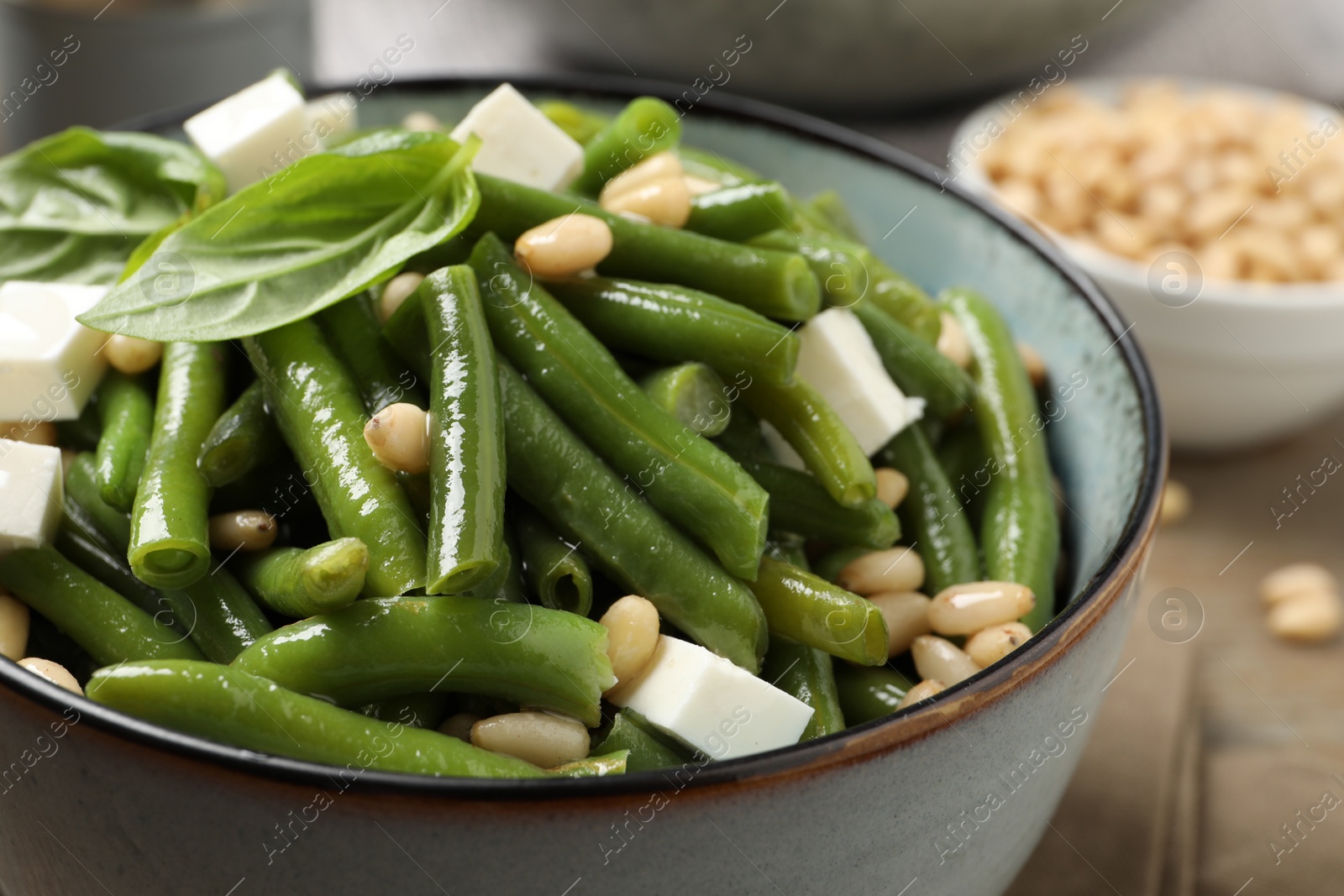 Photo of Delicious salad with green beans, pine nuts and cheese on table, closeup