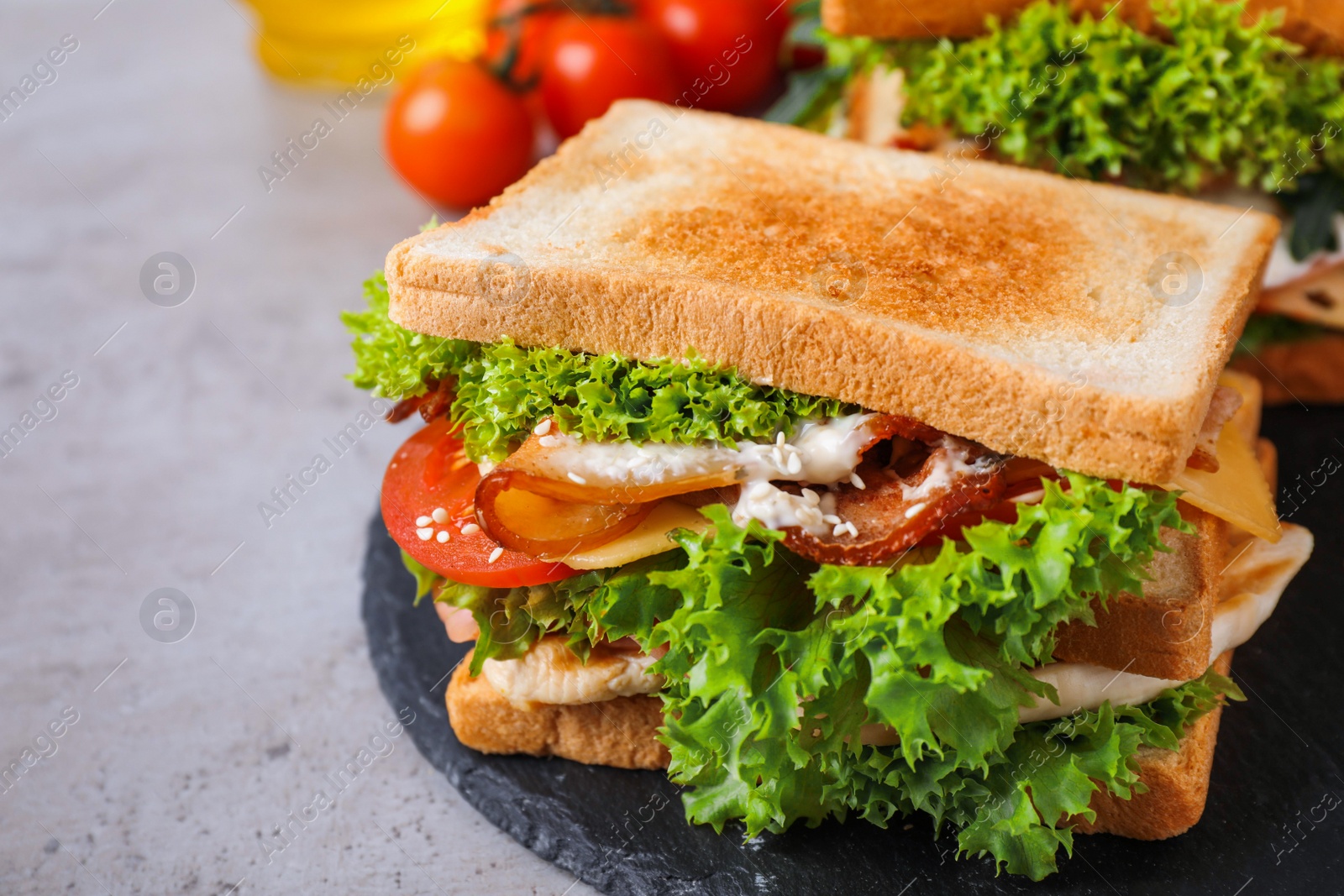 Photo of Yummy sandwich with bacon and chicken on grey table