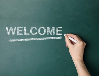 Woman writing word WELCOME on chalkboard, closeup