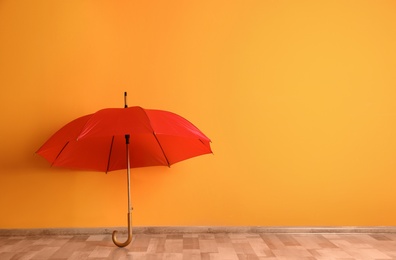 Photo of Beautiful open umbrella on floor near color wall with space for design