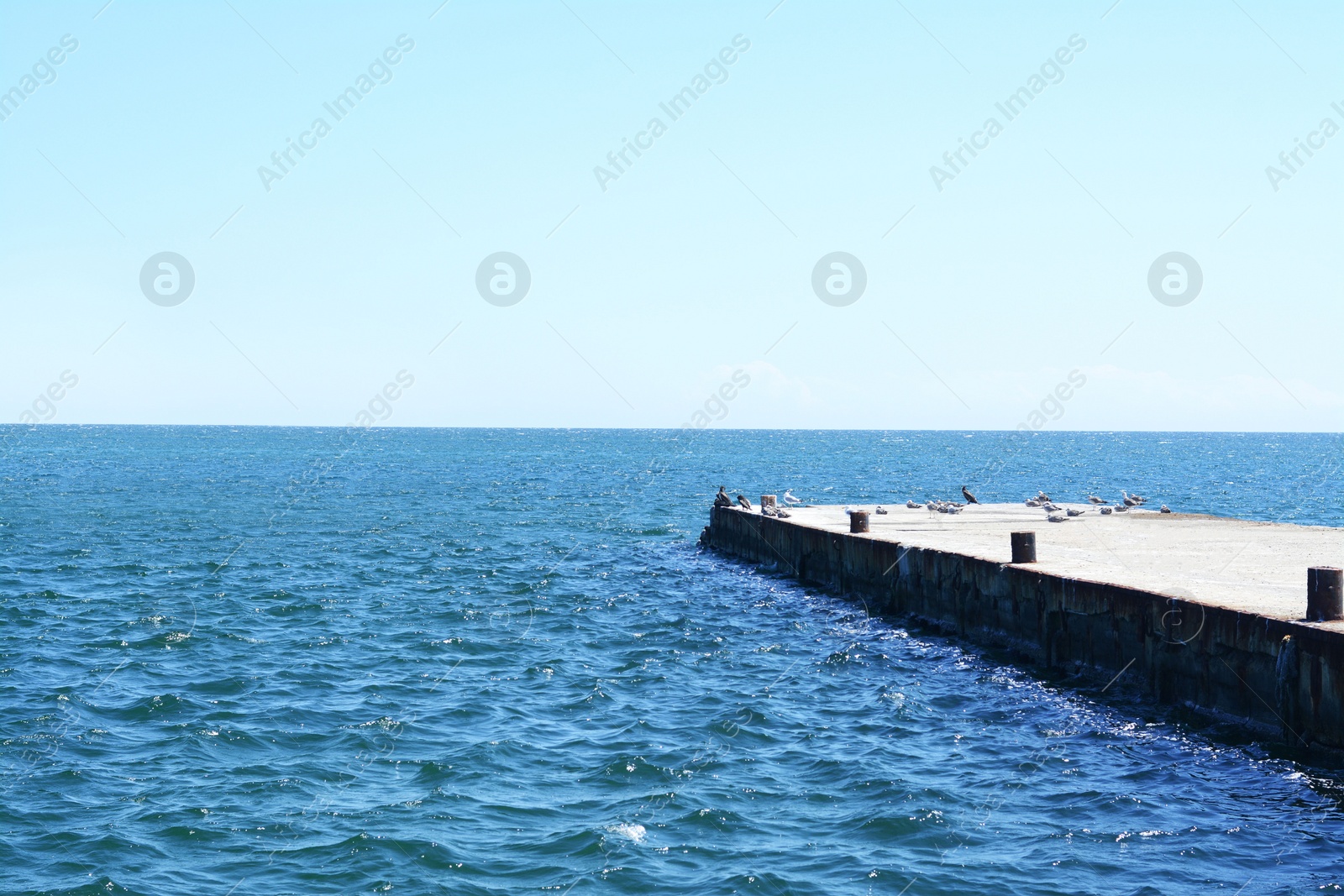 Photo of Beautiful concrete pier in sea on sunny day, space for text