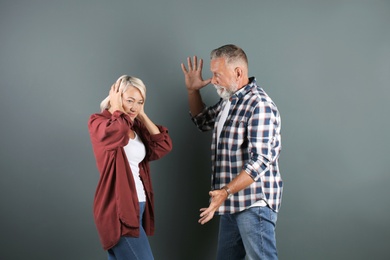 Photo of Mature couple having argument on grey background. Relationship problems