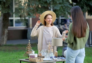 Women shopping on garage sale near table with different items in yard