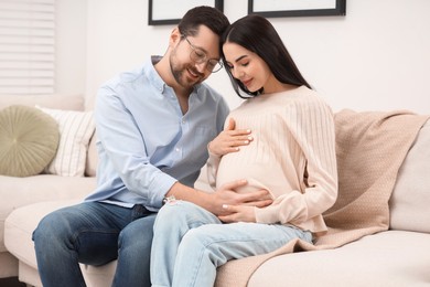 Pregnant woman with her husband on sofa at home