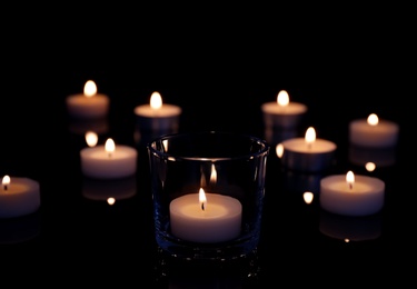 Photo of Beautiful burning wax candles on black background