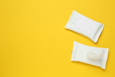 Photo of Wet wipes flow packs on yellow background, flat lay. Space for text 