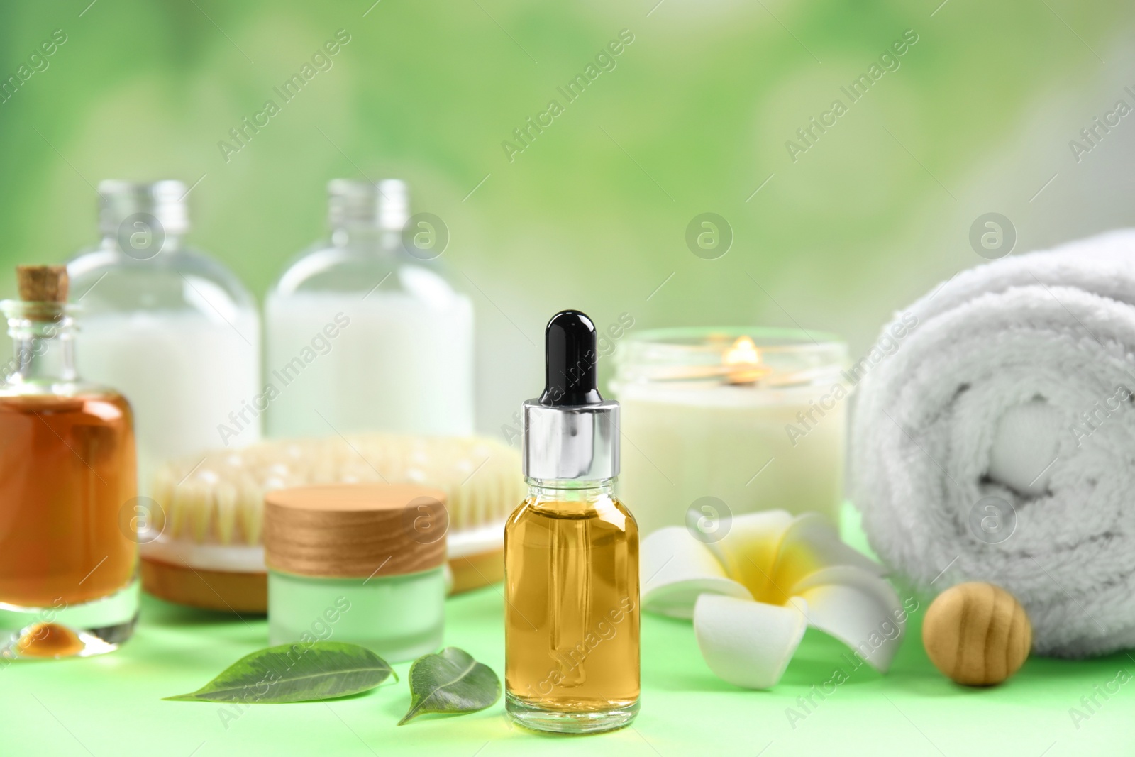 Photo of Composition with spa cosmetic and plumeria flower on green table