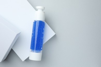Bottle of cosmetic product on light grey background, top view. Space for text