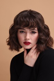 Photo of Portrait of beautiful young woman with wavy hairstyle on beige background