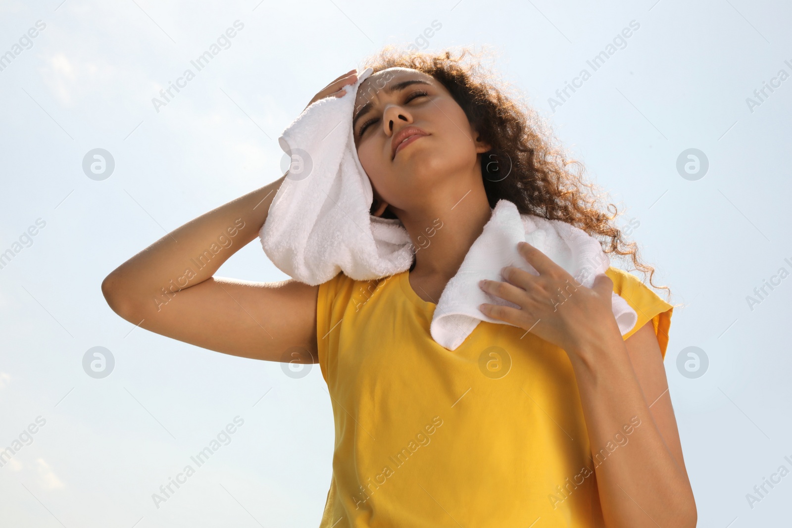 Photo of African-American woman with towel suffering from heat stroke outdoors