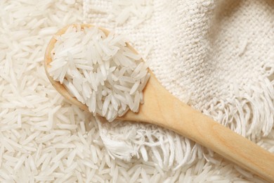 Raw basmati rice, spoon and cloth, top view