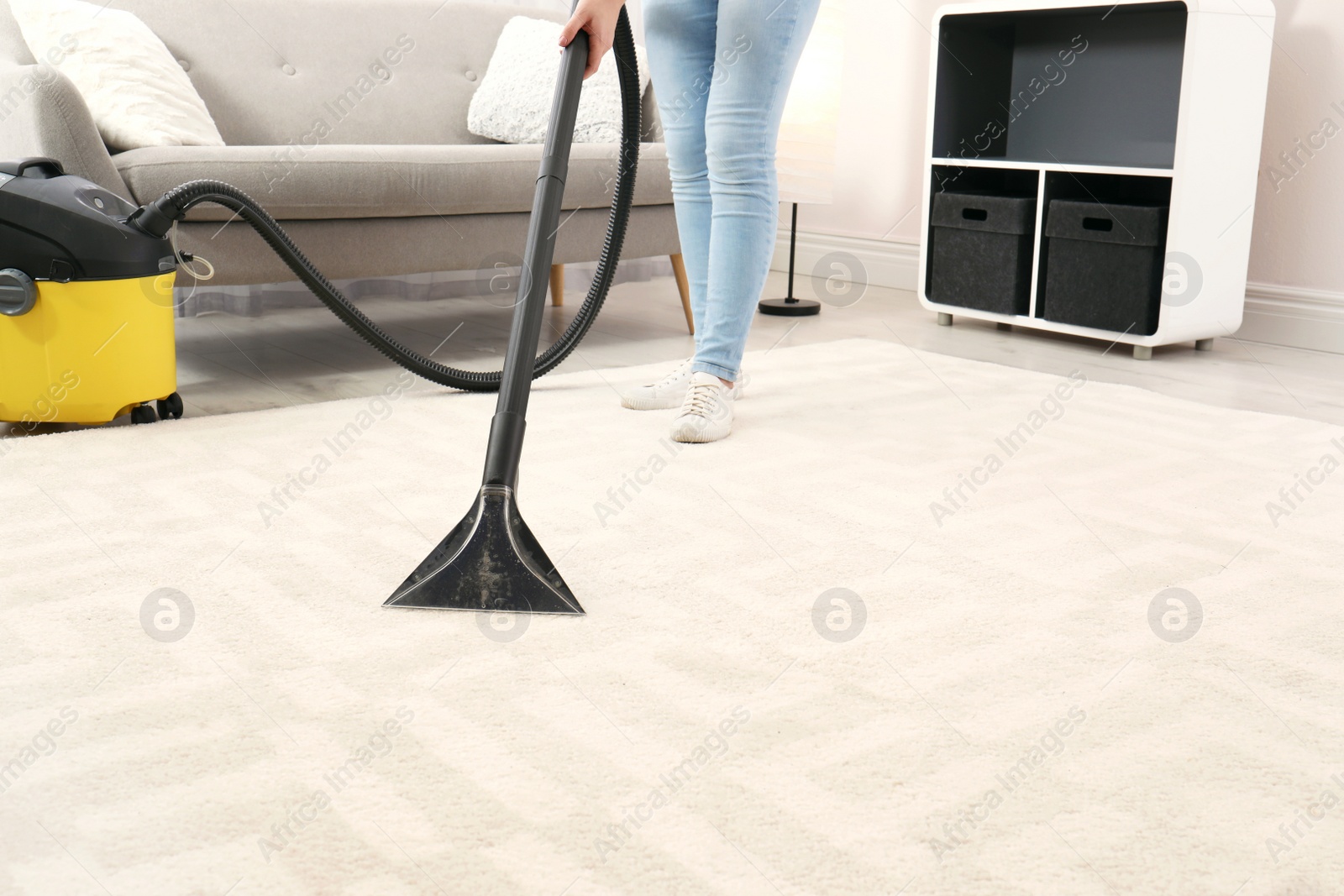 Photo of Woman removing dirt from carpet with vacuum cleaner indoors, closeup. Space for text