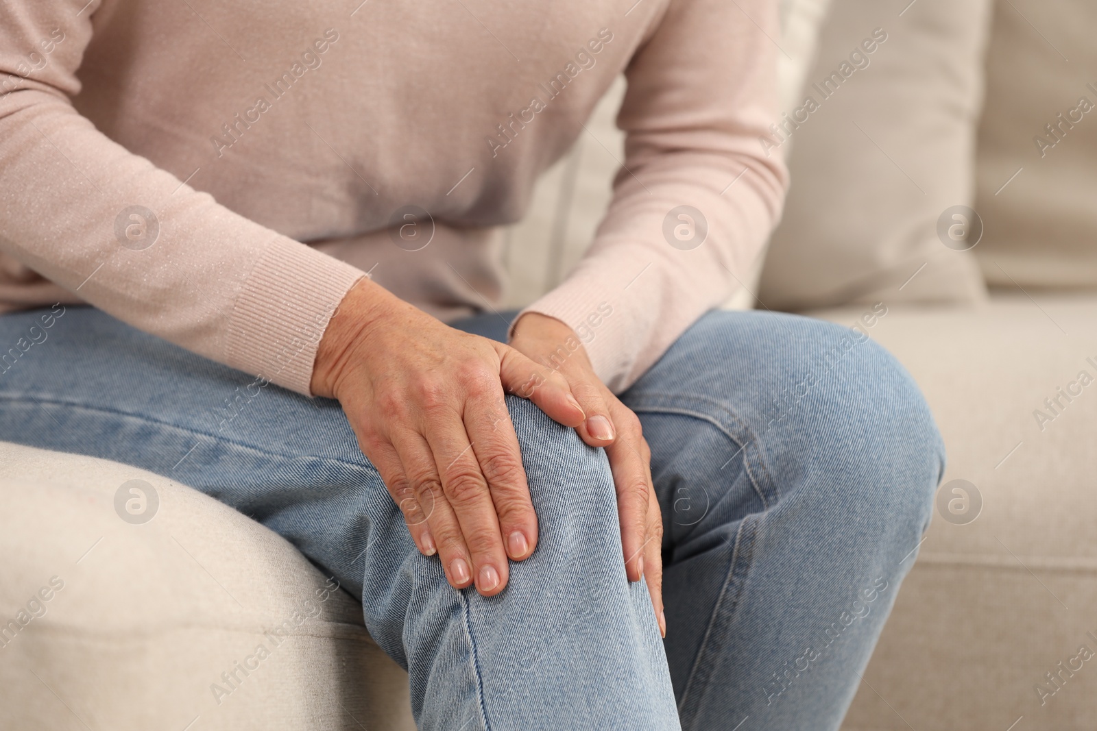 Photo of Mature woman suffering from knee pain on sofa, closeup. Rheumatism symptom