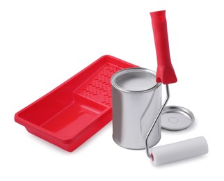 Photo of Can of grey paint, roller and tray on white background