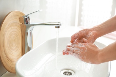 Photo of Woman washing hands indoors, closeup. Bathroom interior