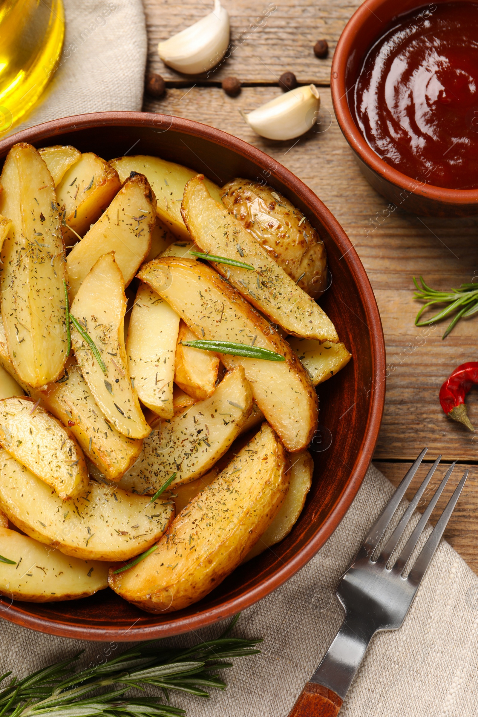 Photo of Delicious baked potatoes with spices served on wooden table, flat lay